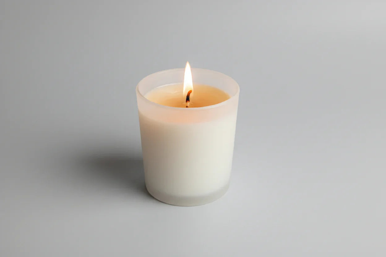 Handgemachte Duftkerze im Glas, brennend, auf hellem Hintergrund, minimalistisch
