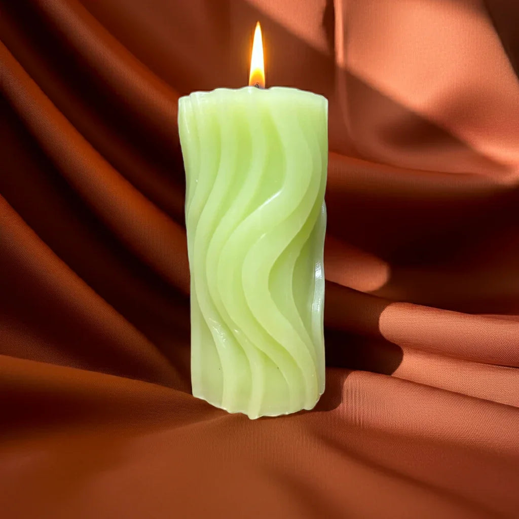 Brennende handgemachte Wellenkerze auf braunem Stoff, dekorative Duftkerze, gemütliches Licht