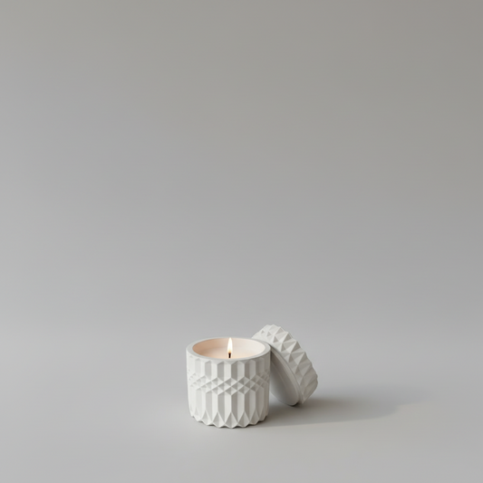 Handgemachte Kerze in weißem, strukturiertem Glas auf Tisch mit Macarons und Blumen, stimmungsvolles Licht