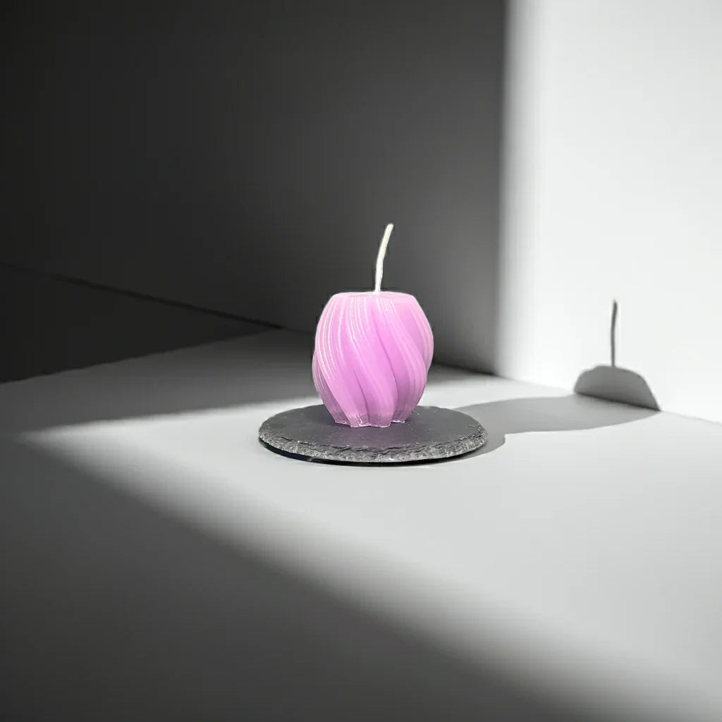 Handgemachte lila Kerze in moderner Form auf Steinteller, minimalistisch beleuchtet