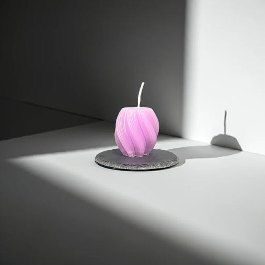 Handgemachte lila Kerze in moderner Form auf Steinteller, minimalistisch beleuchtet
