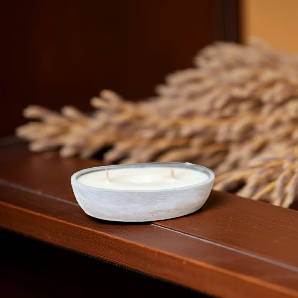 Handgemachte Kerze in weißer Schale mit zwei Dochten, dekorativ auf Holztisch