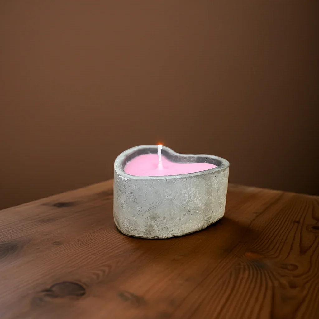 Handgemachte rosa Kerze in Herzform, Betonhalter, auf Holztisch, stimmungsvolles Licht