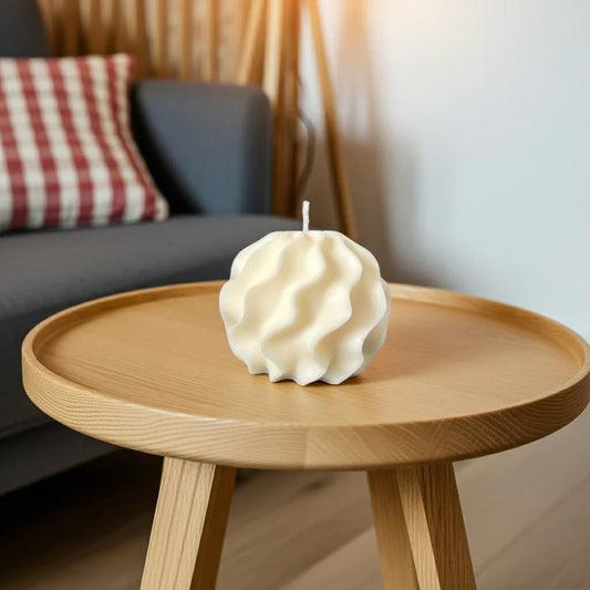 Handgemachte Wellenkerze in Cremefarbe auf rundem Holztisch im Wohnzimmer