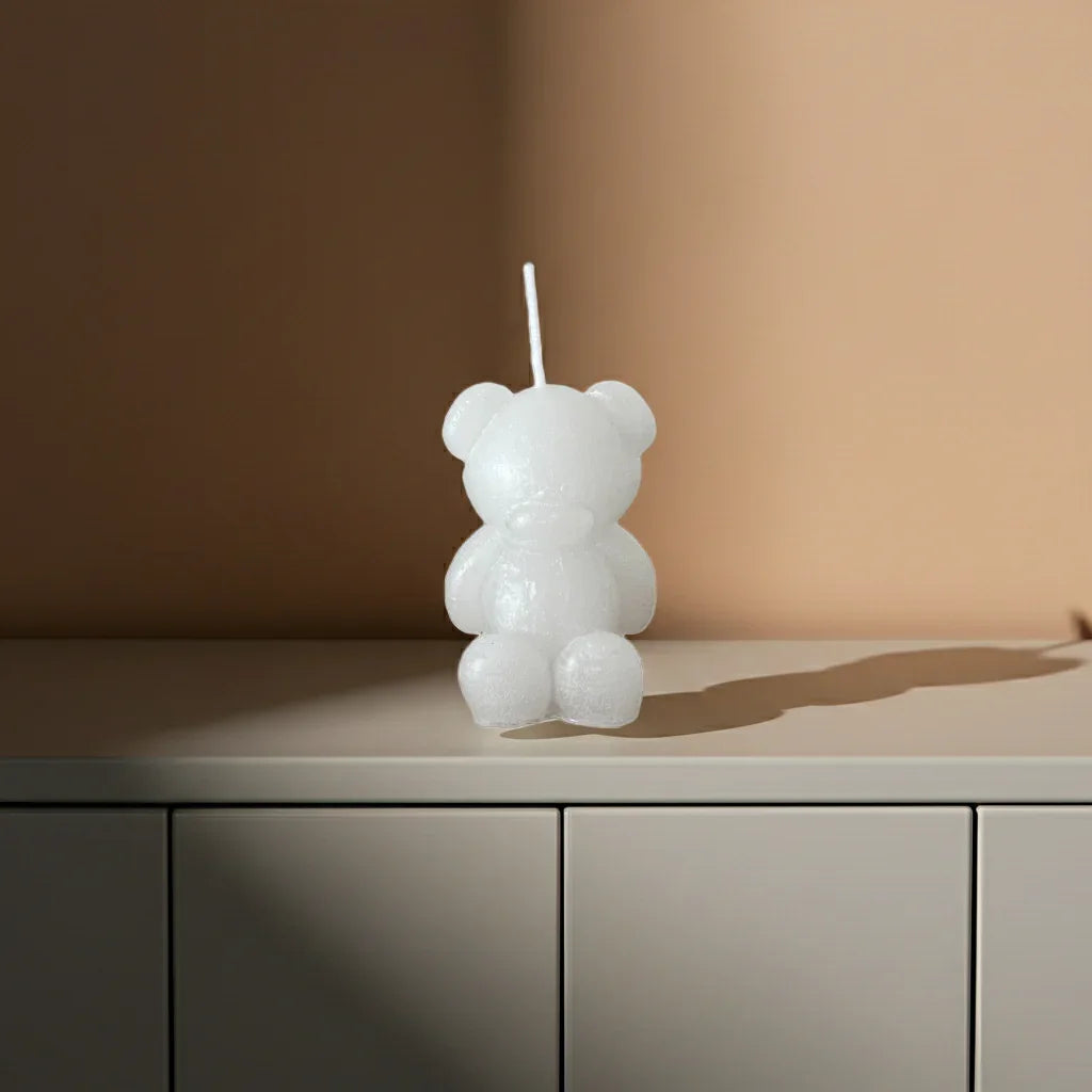 Weiße Kerze in Bärenform aus Wachs auf heller Kommode, minimalistische Dekoration