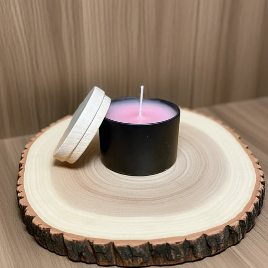 Handgemachte rosa Kerze im schwarzen Glas mit Holzdeckel auf Holzuntersetzer, dekorativ
