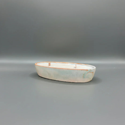 Handgemachte Kerze in ovaler Keramikschale mit drei Dochten, auf grauem Hintergrund