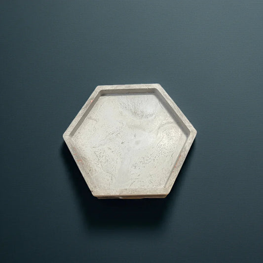 Sechseckige Kerzenschale aus Beton auf dunklem Hintergrund, minimalistisch und modern