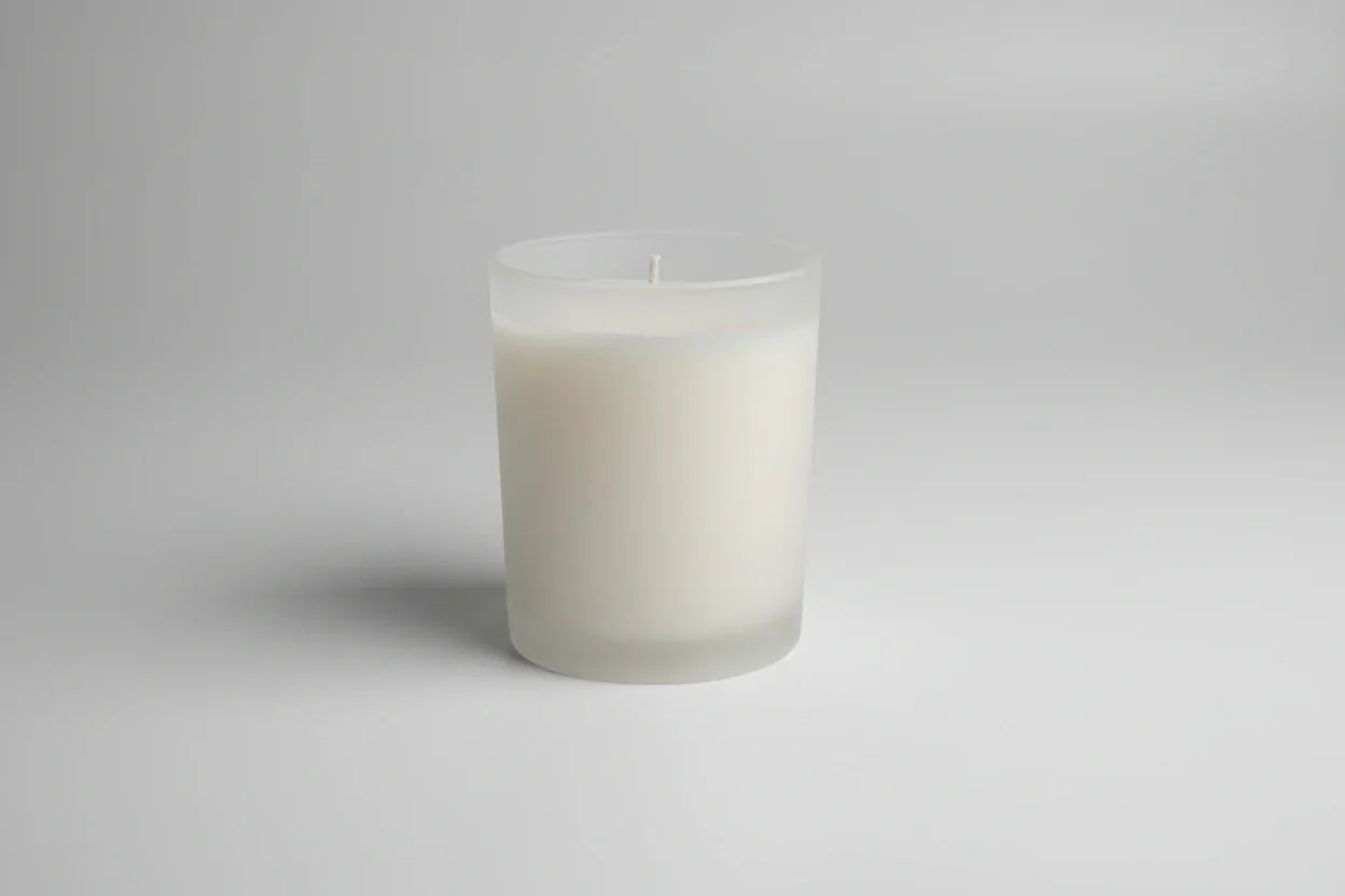 Handgemachte weiße Kerze im Glas auf hellem Hintergrund, minimalistisch und dekorativ